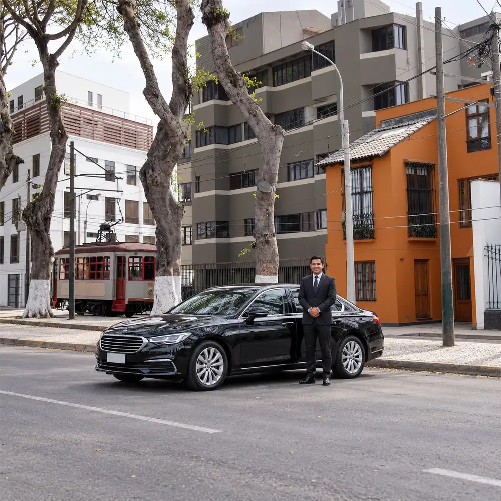 Sedán negro con su conductor junto al tranvía de Barranco